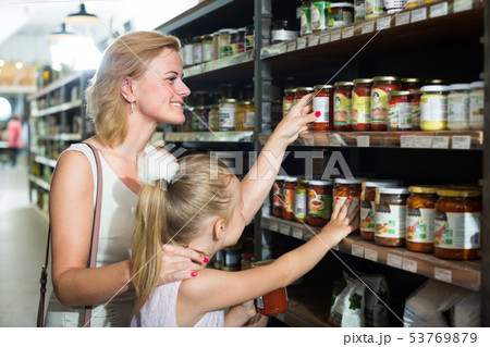 woman with daughter choosing tomato sauce. woman with daughter choosing tomato sauce. 53769879