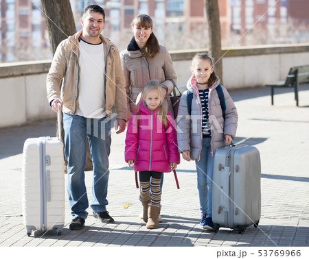 Family portrait of travellers with wheeled trollers in spring day Family portrait of travellers with wheeled trollers in spring day 53769966