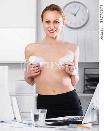 Portrait of naked girl joking with cups in the office 53770672