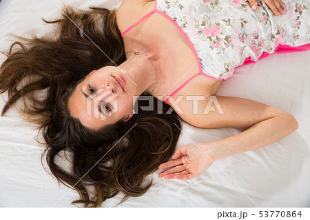 Top view of woman with flowing hair posing in bed in bedroom 53770864