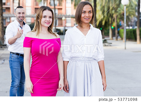 Young women are walking and stranger man is want acquaintance with them 53771098
