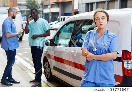Portrait of efficient ambulance paramedic standing near ambulance car Portrait of efficient ambulance paramedic standing near ambulance car 53771647
