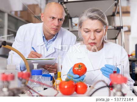 Scientists taking notes while performing experiments Scientists taking notes while performing experiments 53772164