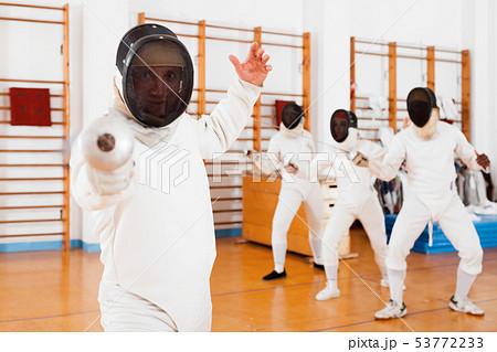 Sporty young man fencer practicing effective fencing techniques in training room 53772233