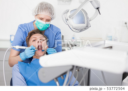 Male patient sitting on chair in dental office getting dentist treatment Male patient sitting on chair in dental office getting dentist treatment 53772504