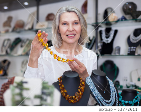Woman trying on a aventurine necklace and earrings at a jewelry store 53772611