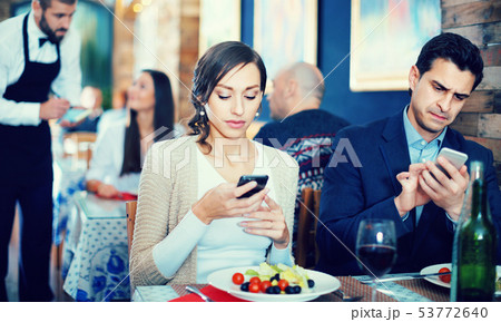 Portrait of man and woman in the restaurant with mobile phones Portrait of man and woman in the restaurant with mobile phones 53772640