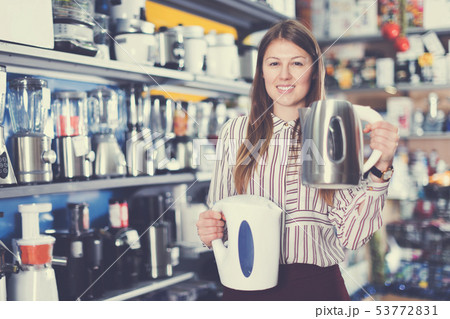 Female seller showing kettles in domestic appliances section Female seller showing kettles in domestic appliances section 53772831