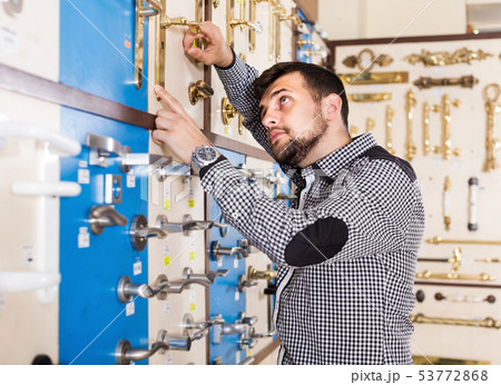 Young man deciding on best door handle 53772868