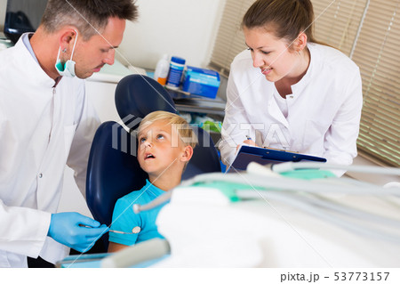 Dentist guy is diagnosing the child while assistant is writing down patient's complaint Dentist guy is diagnosing the child while assistant is writing down patient's complaint 53773157