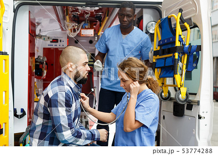 Ambulance team providing medical care to patient 53774288