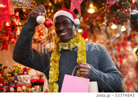 Man in Santa hat looking for New Year decorations Man in Santa hat looking for New Year decorations 53774843