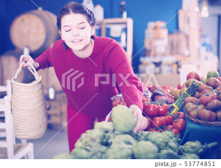 Teenager takes an artichoke 53774851