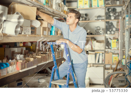 foreman is standing on the stairs near the shelves with boxes foreman is standing on the stairs near the shelves with boxes 53775330