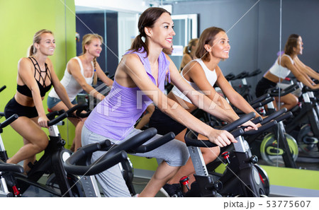 Girls during workout on stationary bicycle in fitness gym 53775607