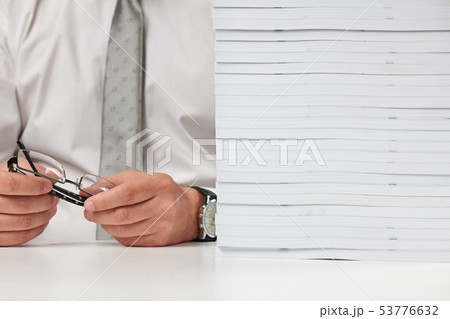 Businessman working at an office, reads stack of 53776632