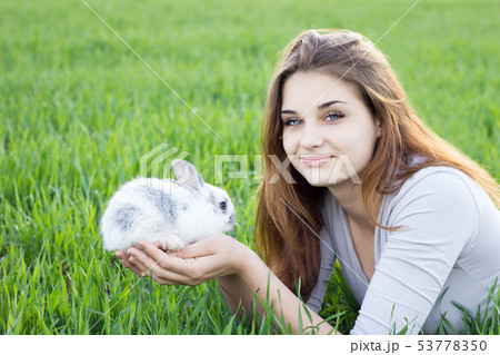 Girl holding a rabbit while on a green meadow. Girl holding a rabbit while on a green meadow. 53778350