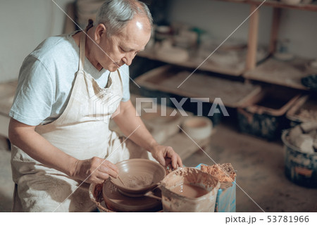 High angle of mature craftsman making clay bowl in potter's studio 53781966