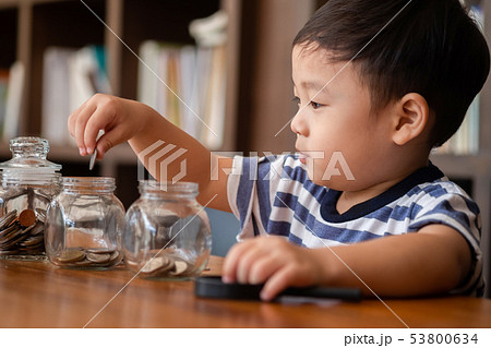cute boy putting money coins in glass,saving money 53800634