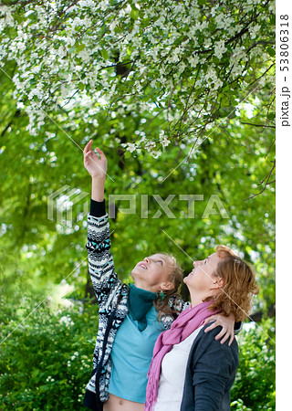 mother and teen daughter under apple tree in the 53806318