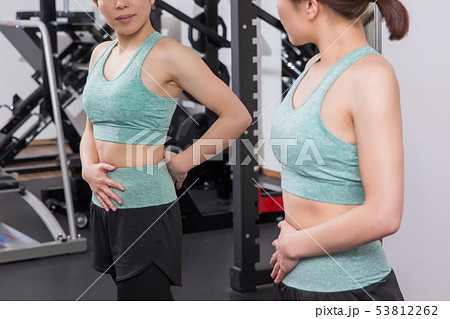 スポーツジムでボディラインをチェックする女性 スポーツジムでボディラインをチェックする女性 53812262