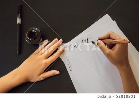 To do list. Calligrapher Young Woman writes phrase on white paper. Inscribing ornamental decorated To do list. Calligrapher Young Woman writes phrase on white paper. Inscribing ornamental decorated 53818801