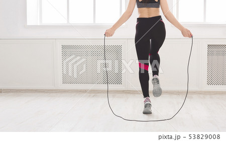 Unrecognizable woman jumping over the skipping rope in studio Unrecognizable woman jumping over the skipping rope in studio 53829008