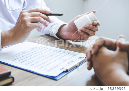 Doctor consulting with patient examining for 53829395