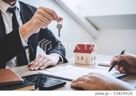 Estate agent giving house keys to client after 53829426