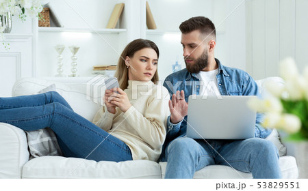 Woman Spying Husband's Laptop, Sitting Together On Sofa 53829551