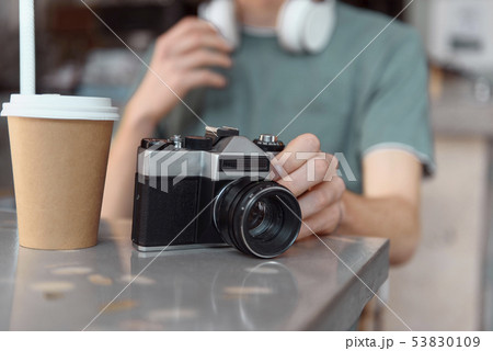 Male with retro camera and hot drink indoors Male with retro camera and hot drink indoors 53830109