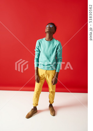 Young Afro American guy in glasses posing on red background Young Afro American guy in glasses posing on red background 53830562