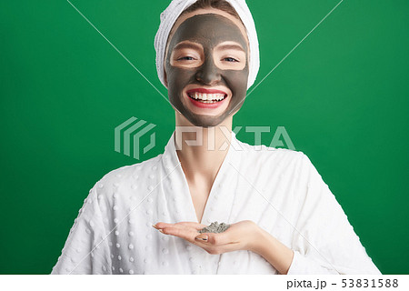 Cheerful girl with towel on her head holding cosmetic clay Cheerful girl with towel on her head holding cosmetic clay 53831588