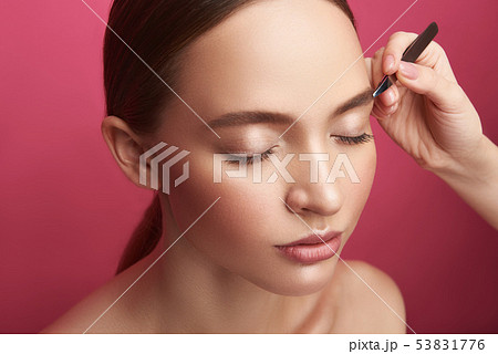 Beautician plucking young lady eyebrows with tweezers Beautician plucking young lady eyebrows with tweezers 53831776