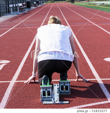 Female sprinter in the starting blocks from behind 53835077