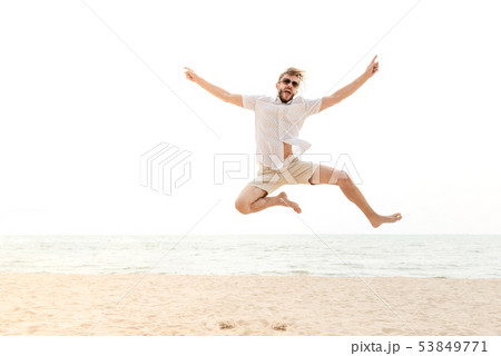 Young energetic happy man jumping at the beach Young energetic happy man jumping at the beach 53849771