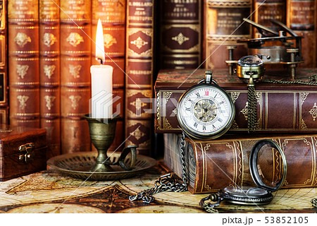 Pocket watch, burning candle and old books 53852105