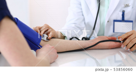 Unknown doctor woman checking blood pressure of female patient, close-up. Cardiology in medicine and Unknown doctor woman checking blood pressure of female patient, close-up. Cardiology in medicine and 53856060