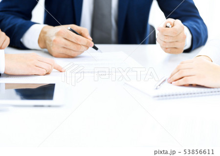 Group of business people and lawyers discussing contract papers sitting at the table, close-up Group of business people and lawyers discussing contract papers sitting at the table, close-up 53856611