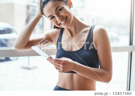 Simply happy. Beautiful and cheerful woman in sportswear and headphones listening music and looking Simply happy. Beautiful and cheerful woman in sportswear and headphones listening music and looking 53857360