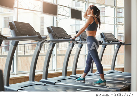 I can not run anymore. Full length of young women in sports clothing keeping hand on forehead and 53857577