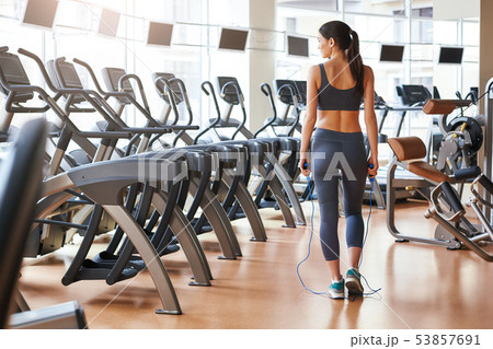 Finishing workout. Back view of short and slim young woman in sportswear standing at gym with jump 53857691