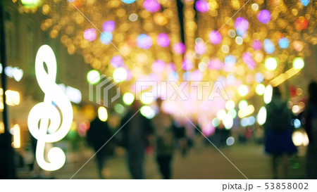 Blurred people walk along illuminated pedestrian street in the evening 53858002