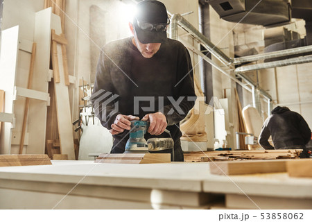 Fine carpentry. Finish carpenters. Worker grinds the wood of angular grinding machine at his Fine carpentry. Finish carpenters. Worker grinds the wood of angular grinding machine at his 53858062