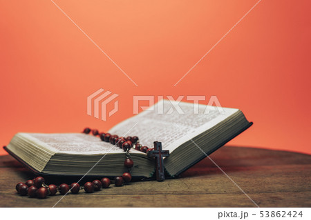 Bible and the crucifix beads on a old round table. Bible and the crucifix beads on a old round table. 53862424