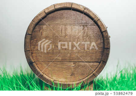Old woden barrel in grass on a gray background. 53862479
