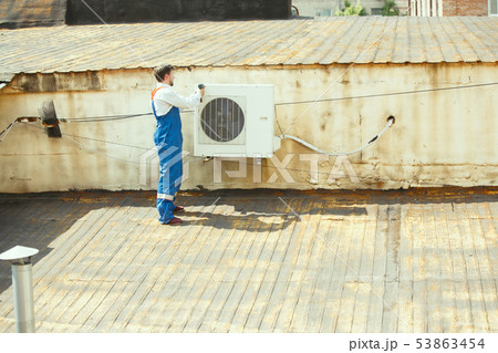 HVAC technician working on a capacitor part for condensing unit HVAC technician working on a capacitor part for condensing unit 53863454