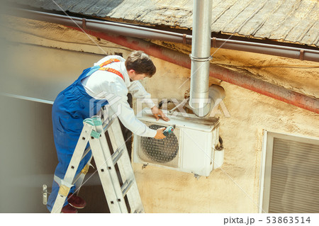 HVAC technician working on a capacitor part for condensing unit HVAC technician working on a capacitor part for condensing unit 53863514