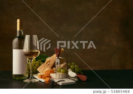 Front view of tasty cheese plate with the wine bottle on dark studio background Front view of tasty cheese plate with the wine bottle on dark studio background 53865469