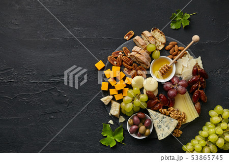 Top view of tasty cheese plate with fruit on the black stone Top view of tasty cheese plate with fruit on the black stone 53865745